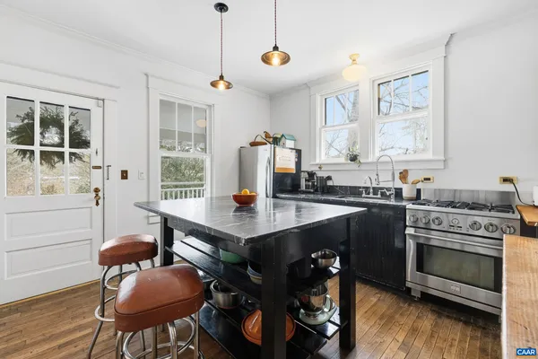 a open kitchen with stainless steel appliances granite countertop a stove a refrigerator a kitchen island a table and chairs