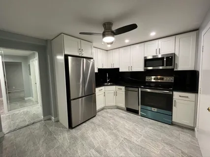 a kitchen with granite countertop a refrigerator and a stove top oven