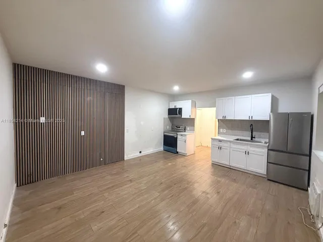 a view of a kitchen with a sink and dishwasher a refrigerator with white cabinets