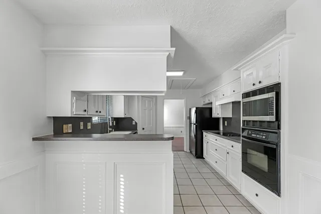 a kitchen with granite countertop a refrigerator a sink a stove and cabinets