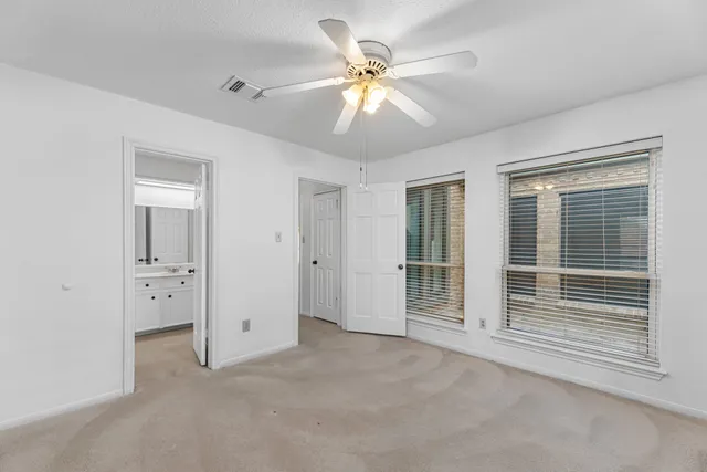 an empty room with a window and a fan
