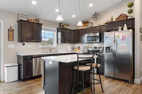 a kitchen with stainless steel appliances granite countertop a refrigerator a stove a sink dishwasher and a microwave with wooden floor