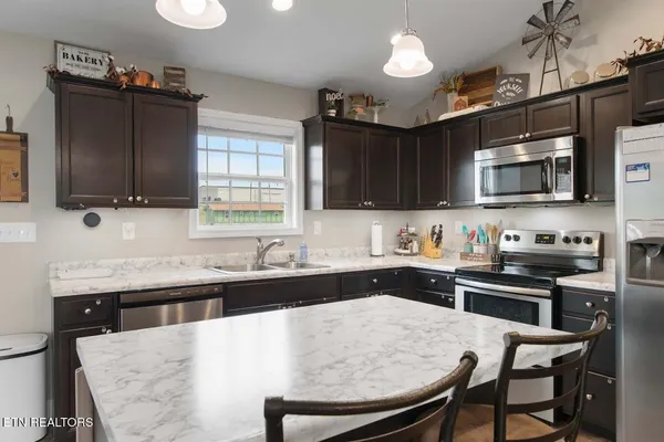 a kitchen with stainless steel appliances a stove a sink a microwave a refrigerator and cabinets
