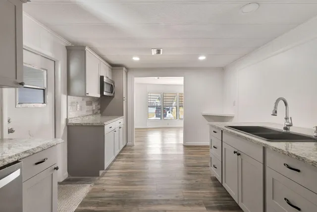 a large kitchen with stainless steel appliances granite countertop a sink stove and refrigerator