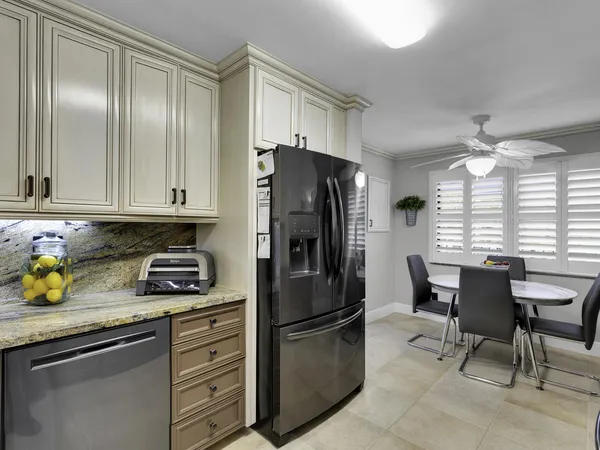a kitchen with stainless steel appliances granite countertop a refrigerator a stove a sink and chairs