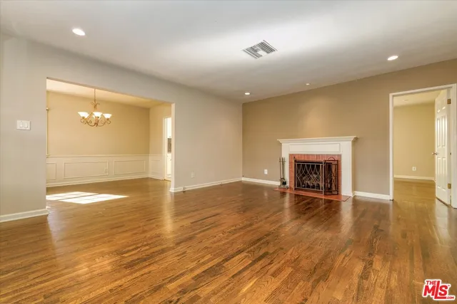an empty room with wooden floor fireplace and windows