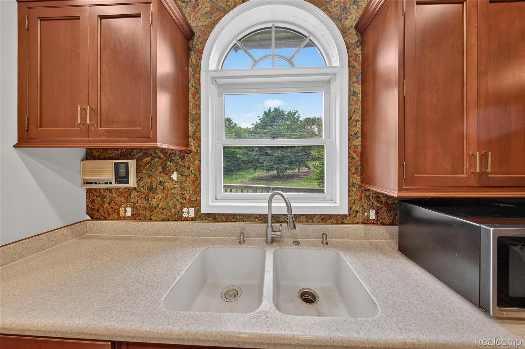 8114 Chilson Road Pinckney, MI 48169 - Photo 7 of 32 Kitchen space featuring a double basin sink with a gooseneck faucet beneath an arched window