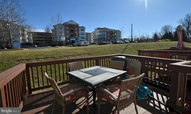 a view of a roof deck with table and chairs a barbeque with wooden floor and fence