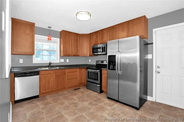 a kitchen with stainless steel appliances granite countertop a refrigerator a stove a sink and dishwasher