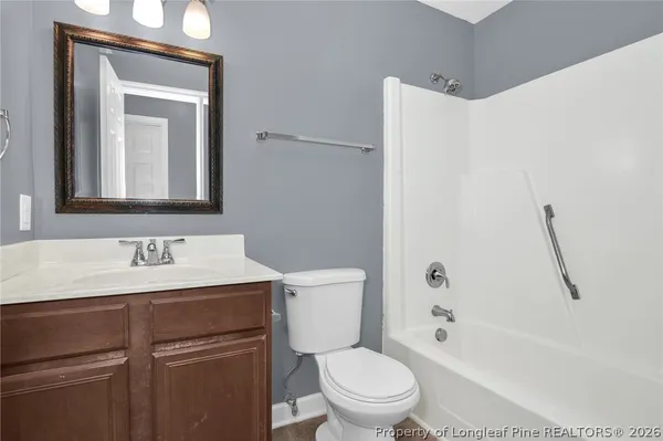 a bathroom with a toilet sink vanity tub and mirror