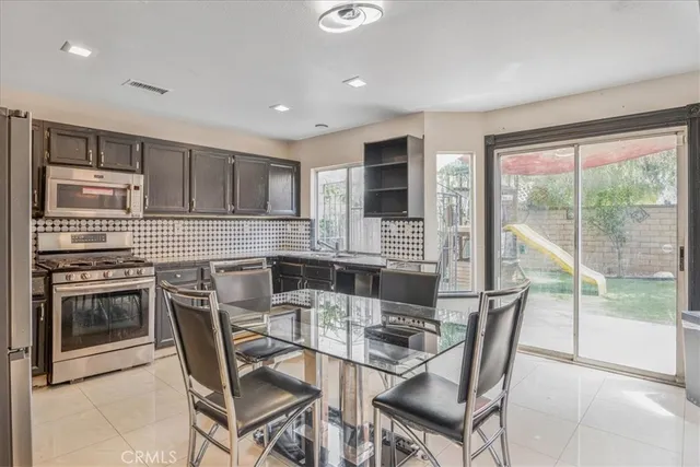 a kitchen with stainless steel appliances granite countertop a stove top oven a sink a dining table and chairs
