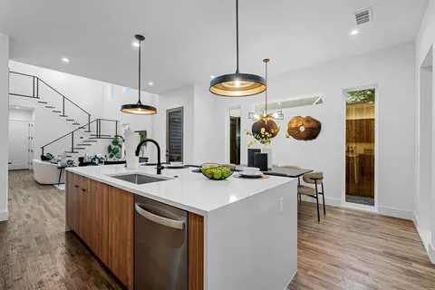 a kitchen with stainless steel appliances granite countertop a sink a stove and a wooden floors