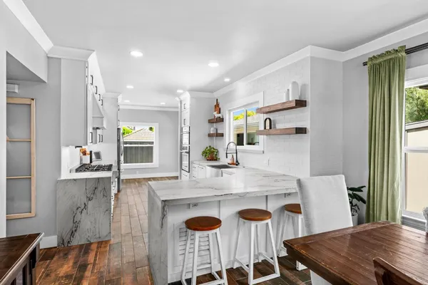 a kitchen with stainless steel appliances granite countertop a stove a sink a refrigerator and a dining table
