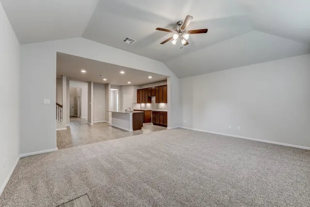 a view of a livingroom with a chandelier fan and kitchen view