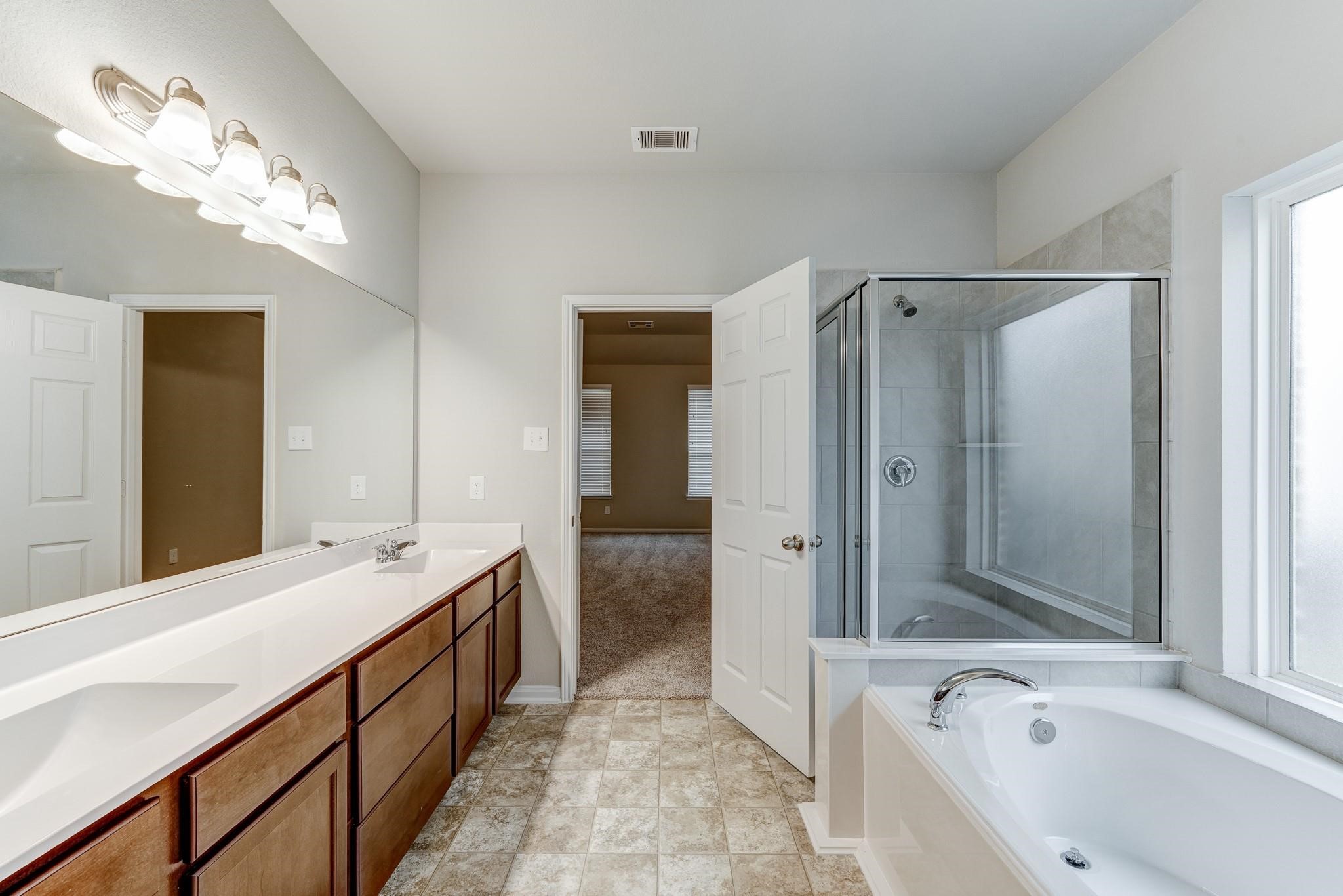 951 Willowick Road Houston, TX 77090 - Photo 8 of 9 a spacious bathroom with a tub a sink and mirrors