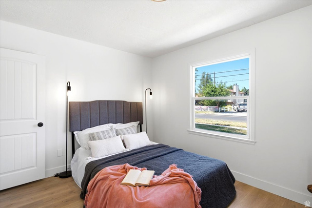 307 Flint Street Layton, UT 84041 - Photo 8 of 13 Bright bedroom featuring a white door with black hardware, wood-finish flooring, and a large window with white trim