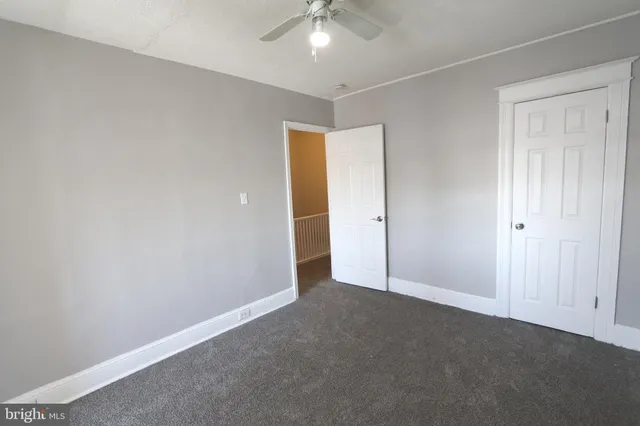 an empty room with a chandelier fan and closet area