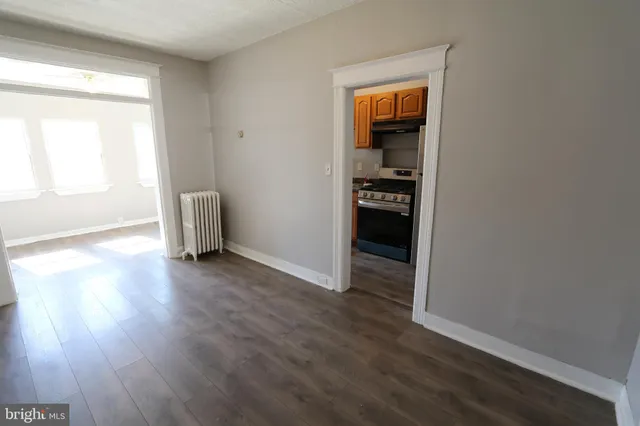 a view of an empty room with wooden floor and closet