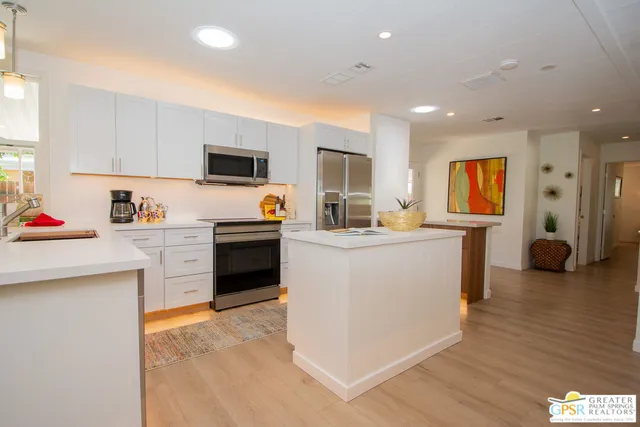 a kitchen with kitchen island a stove a sink a refrigerator and a cabinets