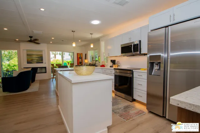 a kitchen with stainless steel appliances kitchen island granite countertop a refrigerator a sink a stove and oven