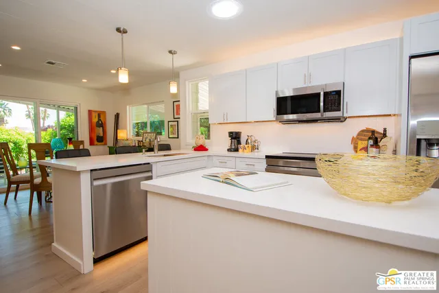 a kitchen with stainless steel appliances a sink a stove a microwave a center island and cabinets