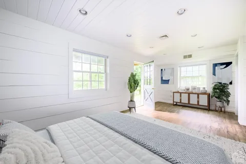 a spacious bedroom with a bed a chandelier and windows