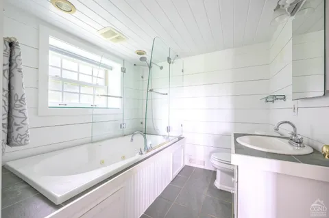 a bathroom with a tub a sink and a large window