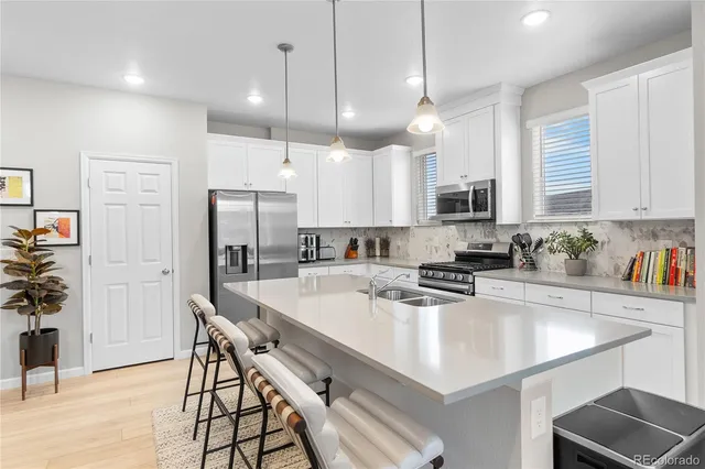 a kitchen with kitchen island a refrigerator a stove a center island a dining table and chairs with wooden floor