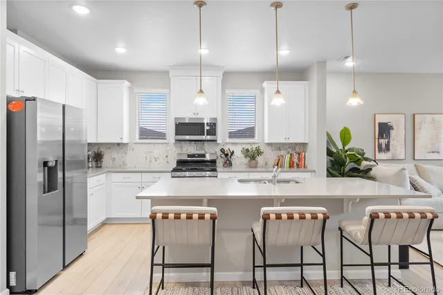 a kitchen with stainless steel appliances kitchen island granite countertop a refrigerator a sink a stove a dining table and chairs