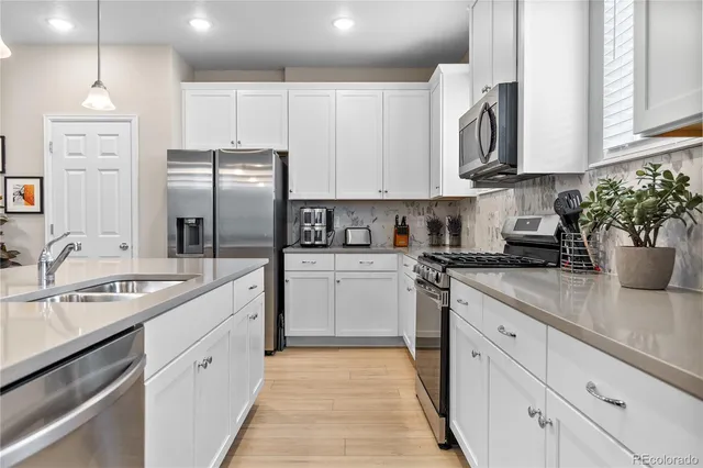 a kitchen with stainless steel appliances granite countertop a sink stove refrigerator and cabinets