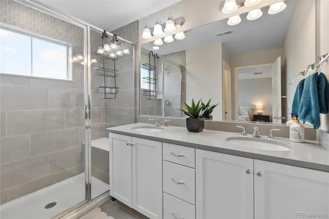 a bathroom with a double vanity sink mirror and shower