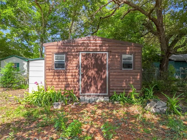 a view of a brick house with a yard and large trees