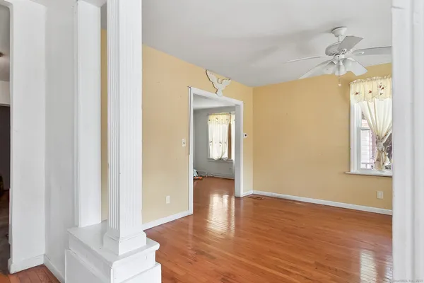 a view of an empty room with wooden floor and a window