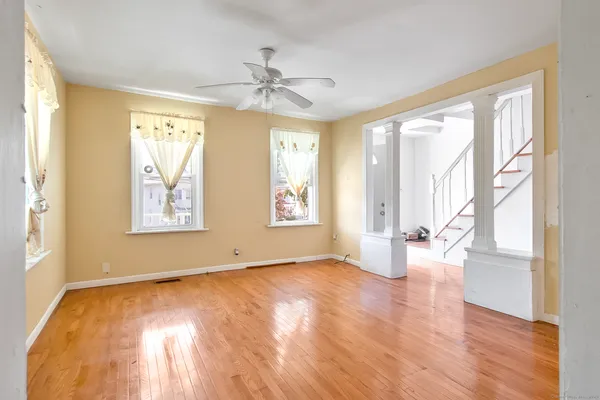 a view of an empty room with wooden floor and a window
