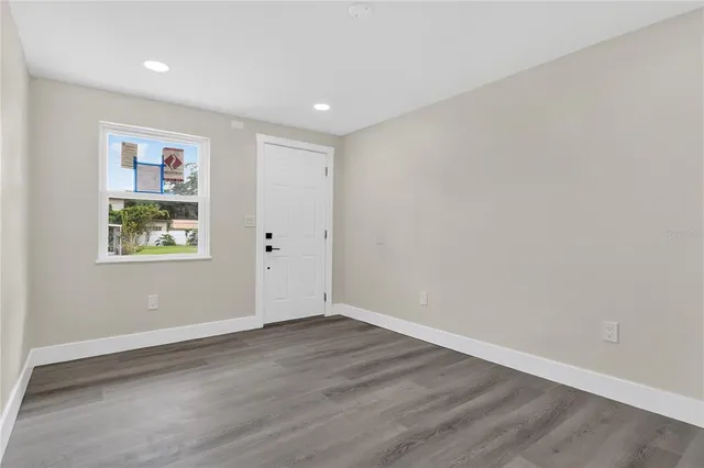 a view of empty room with wooden floor and window