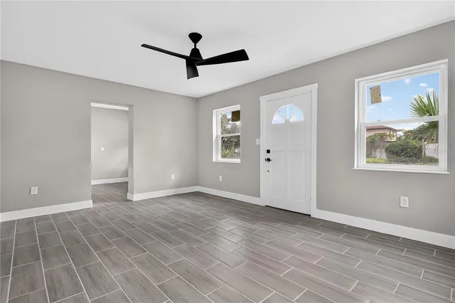 an empty room with wooden floor and windows