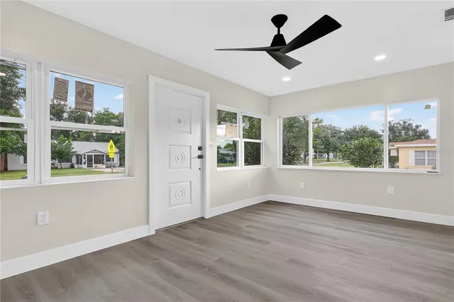 a view of an empty room with wooden floor and windows