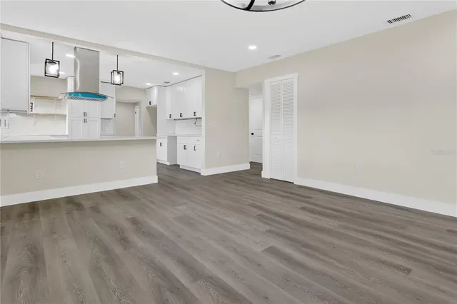 a view of kitchen and empty room with wooden floor