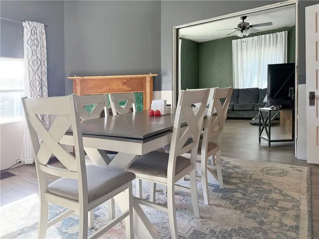 a view of dining room and livingroom with furniture wooden floor a rug a painting and a chandelier