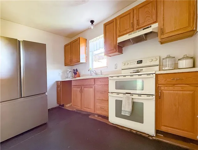 a kitchen with stainless steel appliances granite countertop a sink a stove a refrigerator and cabinets