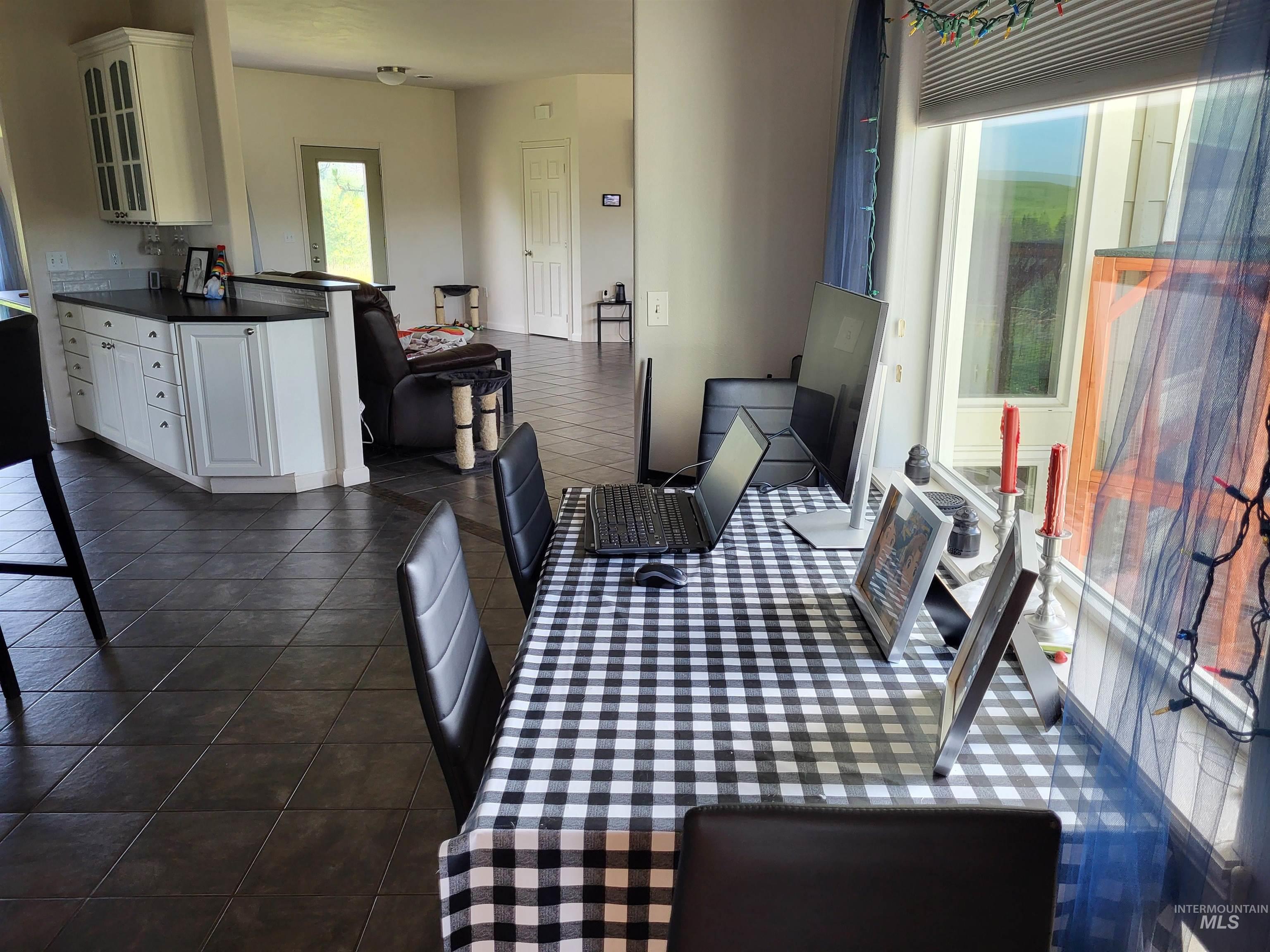 1085 Wallen Road Moscow, ID 83843 - Photo 13 of 50 Spacious interior featuring dark tile flooring throughout, white cabinetry with dark countertops, and ample natural light from multiple windows