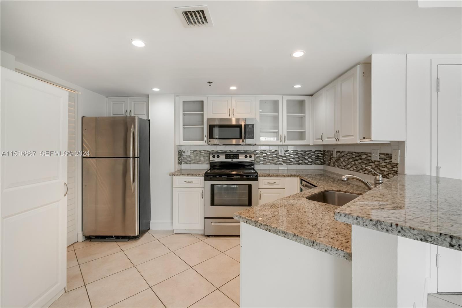 2351 Douglas Road, Unit 1207 Miami, FL 33145 - Photo 6 of 22 a kitchen with granite countertop a refrigerator and a sink