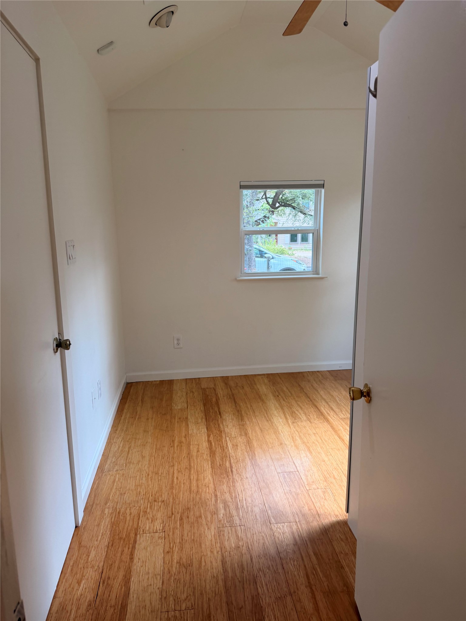 1182 Pandora Street Austin, TX 78702 - Photo 4 of 19 A quiet, well-lit bedroom with warm wood flooring and a view of surrounding greenery.
