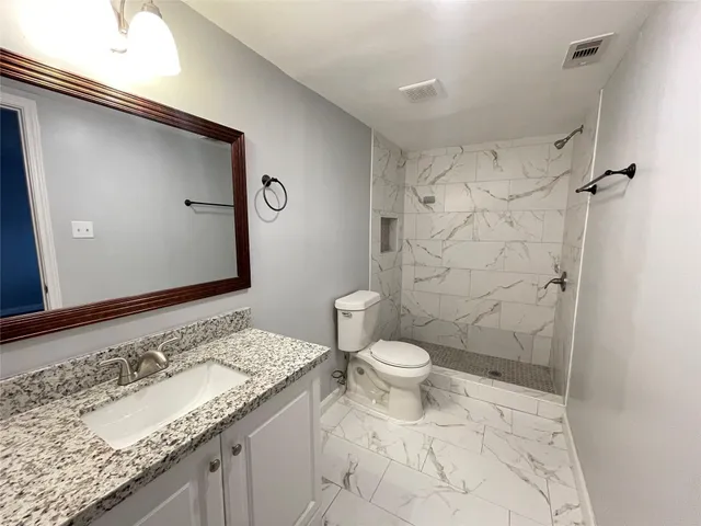 a bathroom with a granite countertop sink toilet and shower