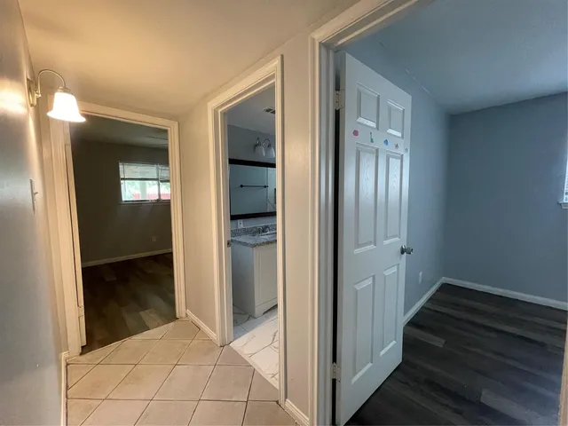 a view of a hallway with wooden floor and a bathroom