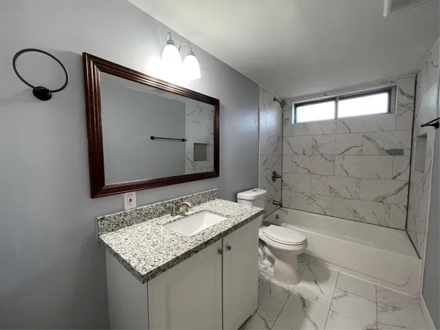 a bathroom with a granite countertop sink toilet and shower