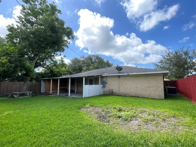a view of a house with a yard and a large tree