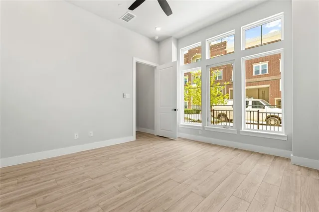 a view of an empty room with a window and wooden floor