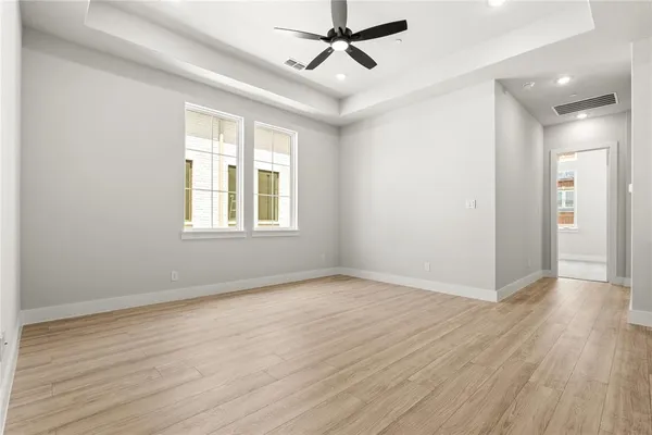 an empty room with wooden floor a ceiling fan and windows
