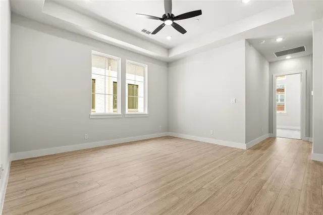 an empty room with wooden floor a ceiling fan and windows